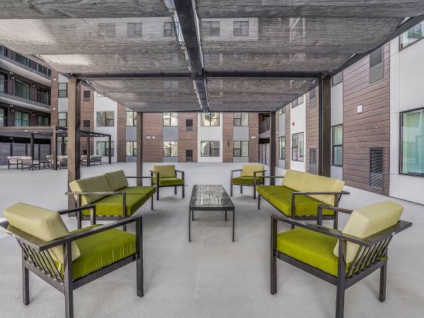 Outdoor courtyard at Solis at Jackson Station featuring shaded seating areas with modern green cushions and open-air views.