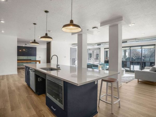 Modern clubhouse kitchen at Solis at Jackson Station featuring a large island with bar seating, pendant lighting, and stainless steel appliances.