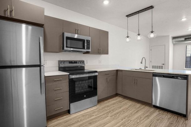 Modern kitchen at Solis at Jackson Station featuring stainless steel appliances, sleek cabinetry, pendant lighting, and wood-style flooring.